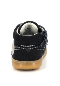 Scarpe in suede nere con chiusura a zip, cuciture bianche e suola in gomma. Etichetta visibile all'interno, che indica la marca e i dettagli di produzione.