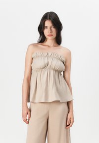 Beige strapless topp med rynket elastisk halslinning og flytende silhuett, laget av lett stoff, parret med matchende beige bukser.