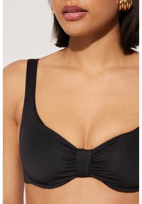 Czarny biustonosz bikini z szerokimi ramiączkami, marszczonym przodem i gładką teksturą. Zaprojektowany z myślą o komforcie i wsparciu.