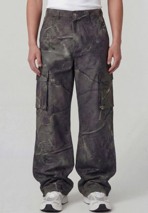 Mørke cargobukser med rette ben, flere store sidelommer og subtil marmoreringsmønster, brukt med hvite joggesko.