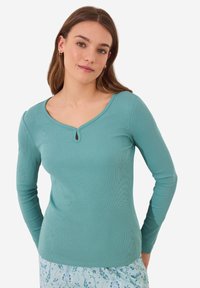 Teal langemouwtopp met een ronde hals die is voorzien van een klein sleutelgatdetail. Geribbelde textuur en aangesloten ontwerp, gecombineerd met een schattige bloemenpatroon broek.