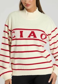 Crème-kleurige trui met rode horizontale strepen, met een oversized pasvorm, hoge hals en een groot "CIAO"-grafiek over de borst.