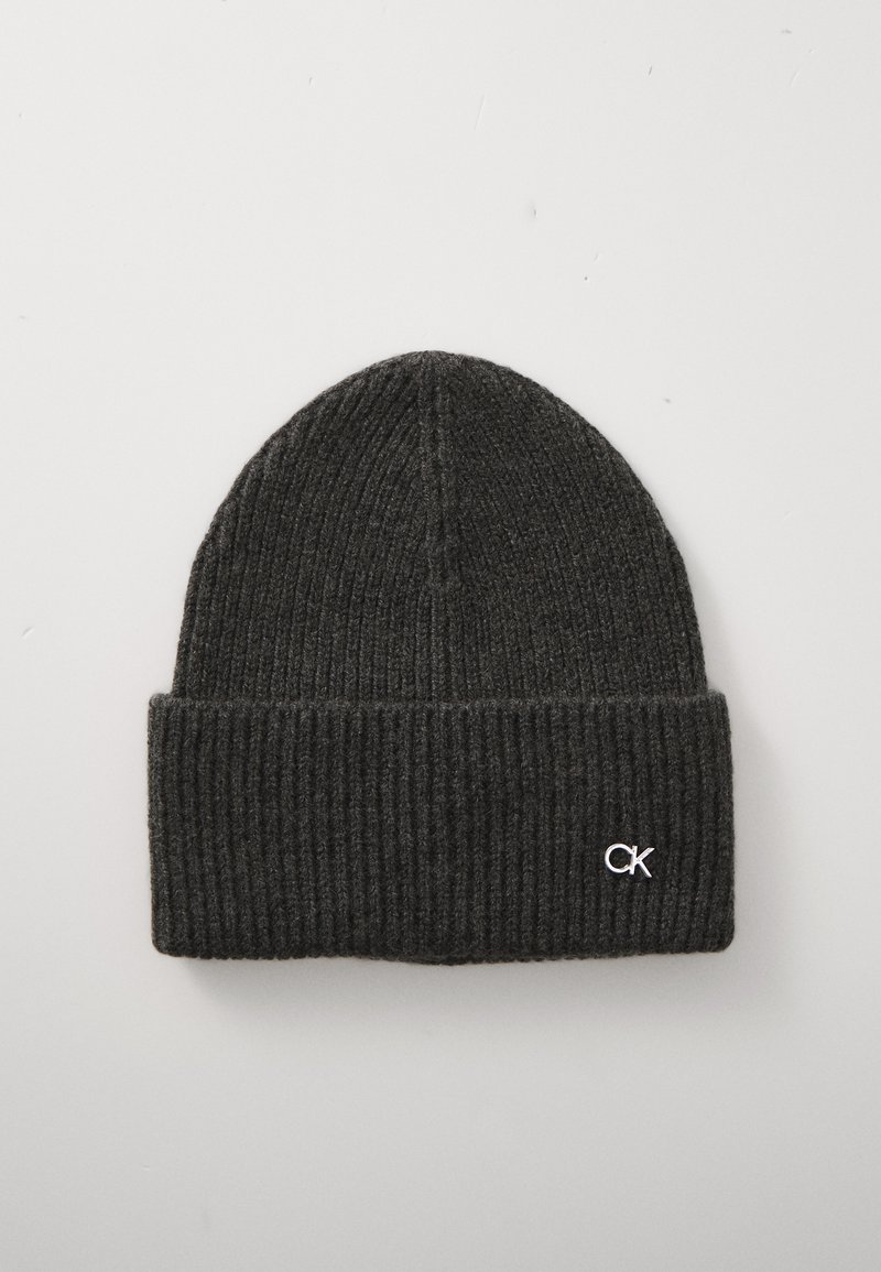 Σκούρο γκρι πλεκτό καπέλο με ραφές και διπλωμένη μπάσα, που διαθέτει ένα μικρό ασημένιο λογότυπο "CK" σε απλή φωτεινή φόντο.
