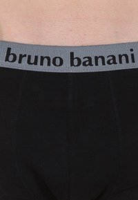 Slip da uomo neri con elastico grigio su cui è scritto "bruno banani" in lettere nere. Tessuto liscio, vestibilità aderente e design semplice.