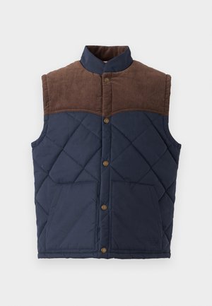 Chaleco acolchado con cuerpo azul marino y paneles de hombros de pana marrón. Presenta un cuello alto y dos bolsillos frontales con cierres de botón.