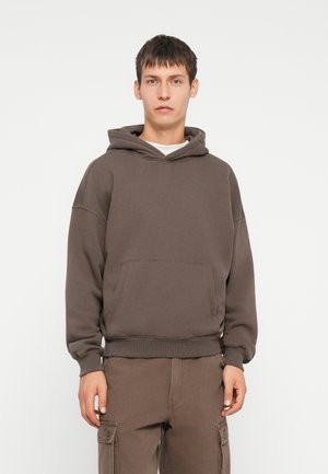 Bruine sweatshirt met een capuchon, geribbelde manchetten en tailleband. Voorzien van een voorzak en een ontspannen pasvorm, gecombineerd met bijpassende broek.