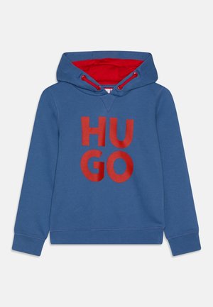 Niebieska bluza z kapturem z czerwonym wnętrzem, z dużym logo "HUGO" w pogrubionych czerwonych literach. Wykonana z miękkiego materiału, z kapturem na sznurki i ściągaczami na mankietach.