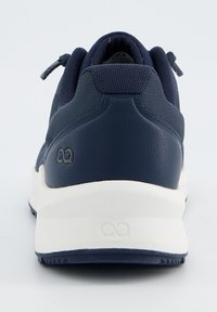 Marineblaue Sportschuh mit einem strukturierten Netz-Obermaterial, glattem Lederabsatz und weißer Sohle. Verfügt über ein minimalistisches Logo am Absatz und eine geschnürte Gestaltung.