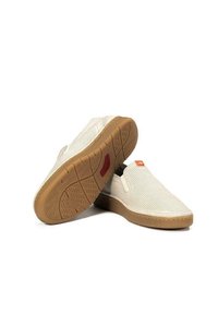 Zapatillas blancas tipo slip-on con textura de malla, suela de goma color tostado y un pequeño acento naranja cerca del talón. Destacan por su diseño ligero y transpirable.