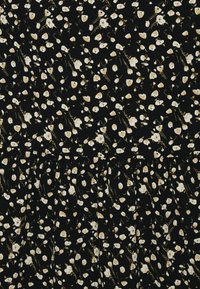 Tecido preto com um padrão floral, apresentando flores brancas com realces amarelos. A textura parece suave, com um detalhe de design plissado na parte inferior.