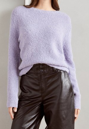 Maglione lilla peloso con collo ampio; abbinato a pantaloni in pelle nera a vita alta con dettagli a bottoni. Texture morbida evidente.