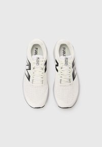 Baskets de sport blanches avec un dessus en maille texturée, des accents noirs et des lacets visibles. Présente le logo "FuelCell Propel" sur la languette.