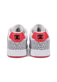 Biele tenisky s textúrovanou čiernou a bielou vzorovanou pätou, červenými akcentmi na päte a čiernym logom. Hladká koža a gumová podrážka.