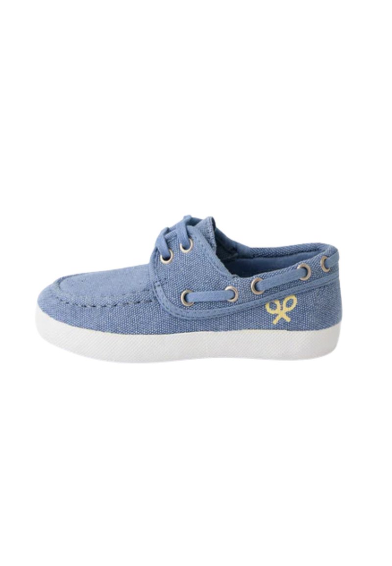 Zapatilla de lona azul con suela de goma blanca, punta redonda y cordones bicolor. Presenta un detalle del logo amarillo en el lado. Diseño clásico de cordones.