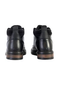 Bottines en cuir noir avec des accents en daim et un talon en bois brun. Présentent un bout arrondi et un panneau dorsal texturé.