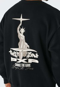 Zwarte sweatshirt met een afbeelding van een gestileerde Vrijheidsbeeld die stervormen vasthoudt boven de tekst "PXP CHANGE THE GAME Project H Parijs."