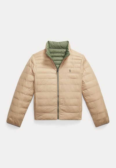 Bēša pūkains jaka ar zaļu iekšējo apkakli, horizontālām šuvēm, rāvējslēdzēju priekšpusē un mazu logotipu kreisajā krūtī. Gluda tekstūra un viegla konstrukcija.