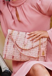 Borsa in tweed rosa con hardware dorato, chiusura a pattina e tracolla a catena. Caratteristiche notevoli includono un logo "LL" e texture accentuate.