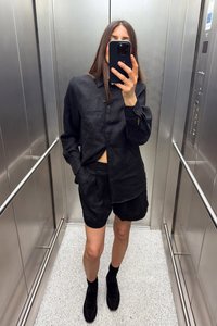 Black linen button-up shirt with long sleeves, paired with high-waisted black shorts, and black socks with black shoes, in an elevator.