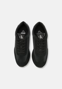 Mustat urheilukengät, joissa on yhdistelmä sileää nahkaa ja samettia. Pyöreä varvas, nauhakiinnitys ja teksturoitu kumipohja.