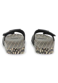 Par črnih natikačev s prilagodljivimi trakovi in črno-bež geometrijsko vzorčastimi podplati, pogled s hrbta.