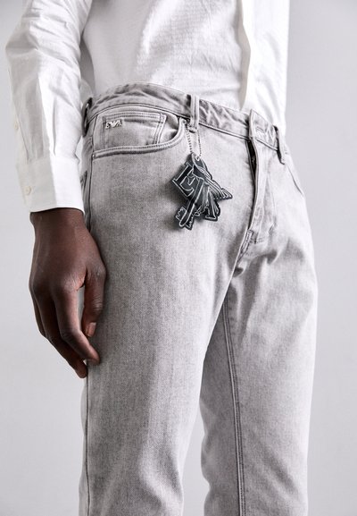 Gray denim jeans with a fitted design, casual style, accented by a black keychain attachment featuring stylized letters.