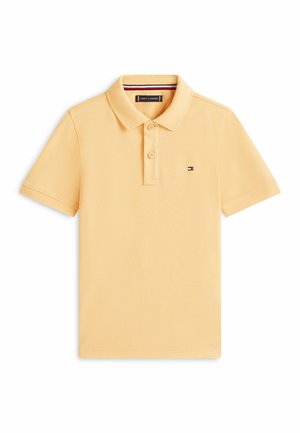 Polo amarillo de manga corta con dos botones, pequeño logo de bandera Tommy Hilfiger en el pecho y cuello acanalado con ribete rojo, blanco y azul.