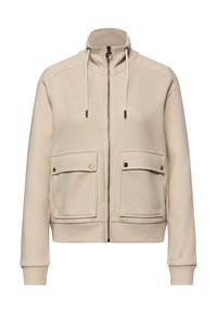 Veste beige zippée avec col montant, deux poches avant, poignets côtelés et capuche à cordon de serrage. Matière douce, design épuré.