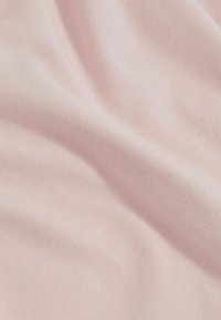 Lys pink stof med en glat tekstur og fint strikket væv, der viser subtile folder og et blødt udseende.
