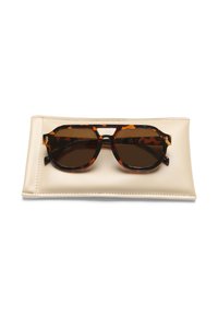 Tortoiseshell sunglasses with brown lenses on a beige protective case. Features rounded frames and a bridge cutout.