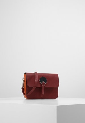 Kompaktowa bordowa skórzana torebka na ramię z klapką, okrągłą czarną metalową klamrą i regulowanym paskiem, prezentowana na białym tle.