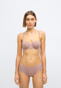 Svetlo fialová podprsenka s tvarovanými košíčkami a tenkými nastaviteľnými ramienkami, doplnená o zodpovedajúce nohavičky s vysokým pásom. Jemná textúra s minimálnymi detailmi.