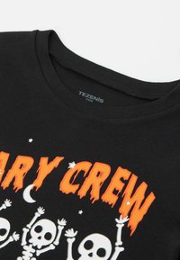 Schwarzes Baumwoll-T-Shirt mit einem grafischen Design, das orangefarbene Schriftzüge mit "Scary Crew", Skeletten sowie Stern- und Mondakzenten zeigt.