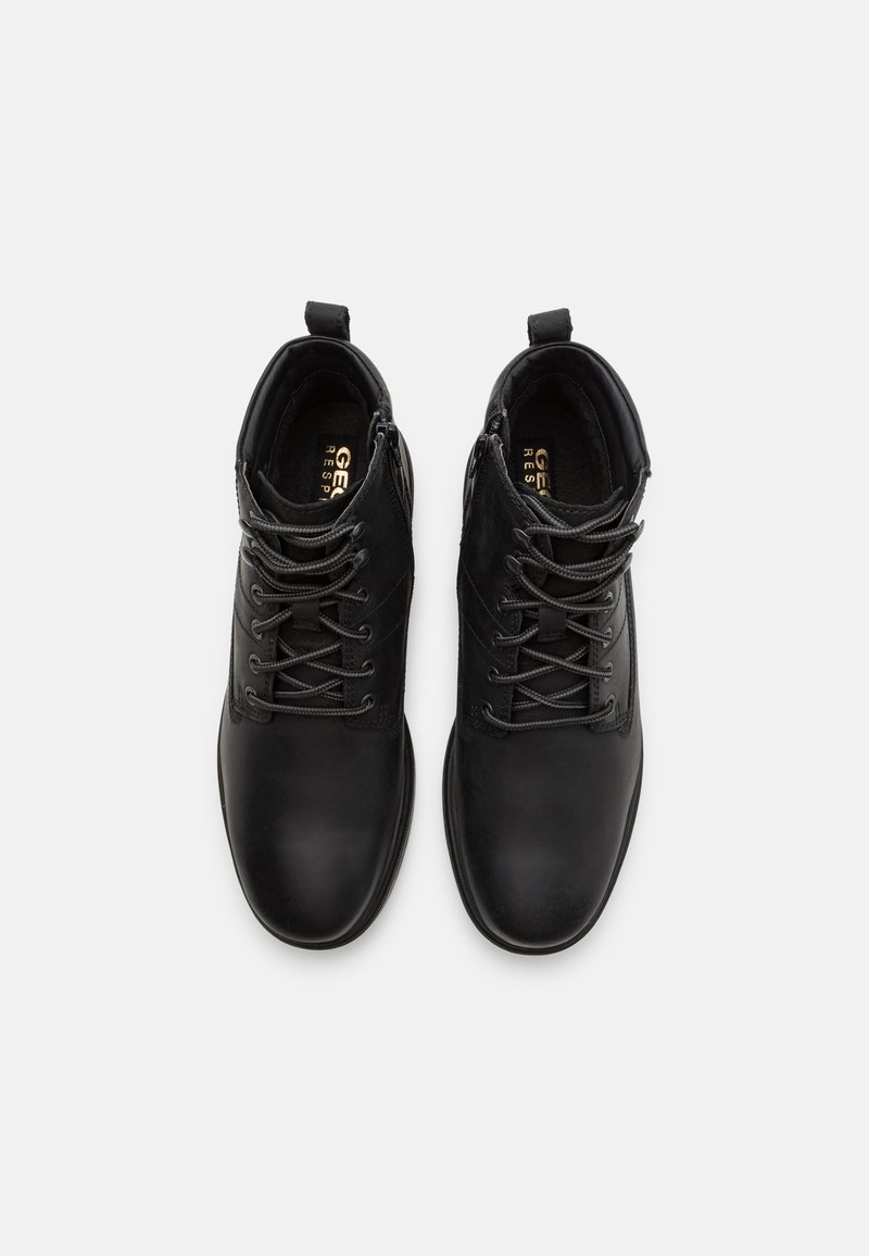 Schwarze Leder-Ankle-Boots mit Wildlederakzenten, runder Zehenform, Schnürung vorne und Zugschlaufen an der Ferse für ein leichtes Anziehen.