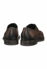 Scarpe di pelle marrone con una superficie liscia, punta arrotondata e tacco basso. Presentano cuciture sottili lungo i bordi e un design semplice.