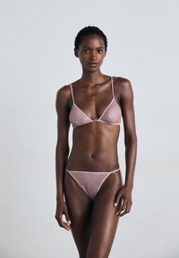 Roze mesh bikini met dunne banden, bestaande uit een driehoekige bralette en een onderkant met minimale bedekking; geaccentueerd met een klein detail in zilverkleurig hardware.