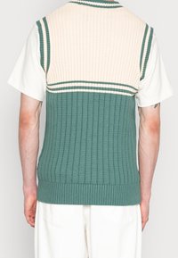 Strick-Weste ohne Ärmel in Grün und Creme, mit geripptem Textur, gestreiften Akzenten und einem flachen Kragen.