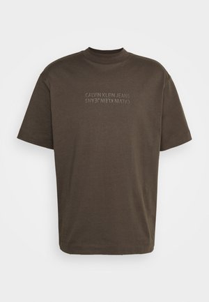 Brązowy bawełniany t-shirt z krótkimi rękawami, okrągłym dekoltem i napisem "CALVIN KLEIN JEANS" nadrukowanym na przodzie w jaśniejszym odcieniu.