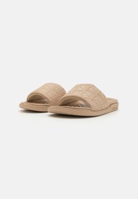 Beige szandál csúszkák textúrált anyagból, gyémántmintával a pántokon és sík, párnázott talppal a kényelem érdekében.