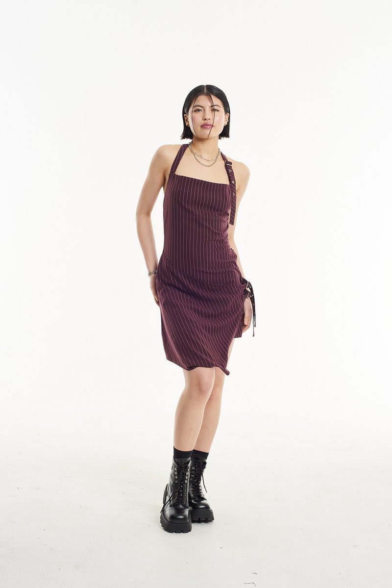 Rochie maronie cu dungi subțiri, cu decolteu halter, detaliu cu legare pe lateral și croi lejer. Purtată cu cizme de luptă negre, cu șireturi.