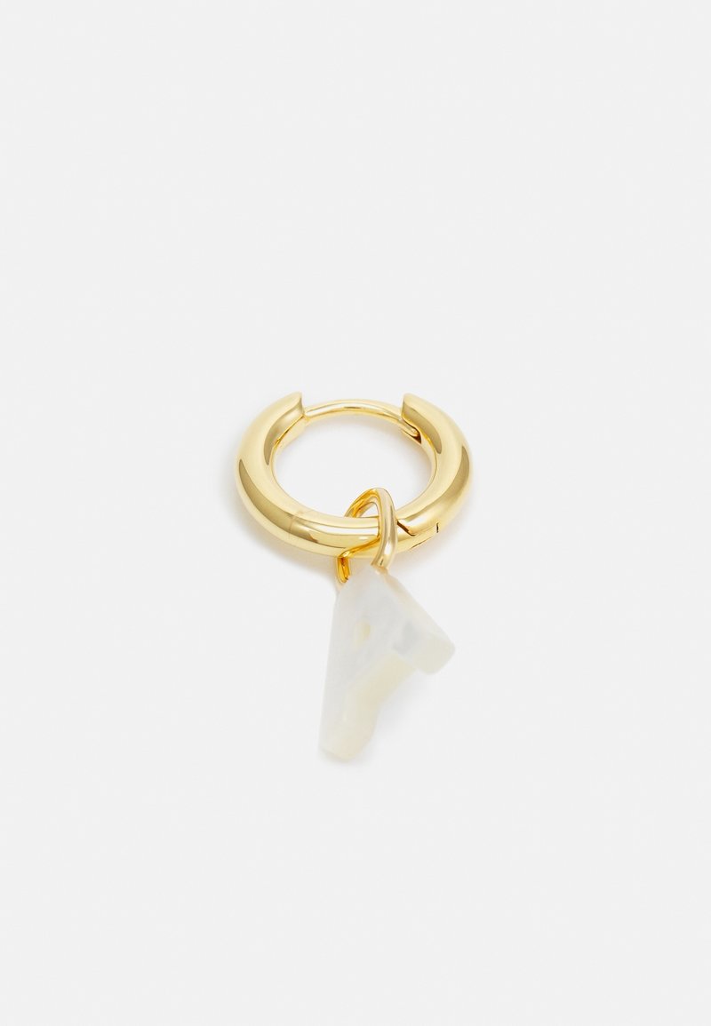 Boucle d’oreille anneau en or avec un petit pendentif blanc triangulaire suspendu dessus sur un fond blanc uni.