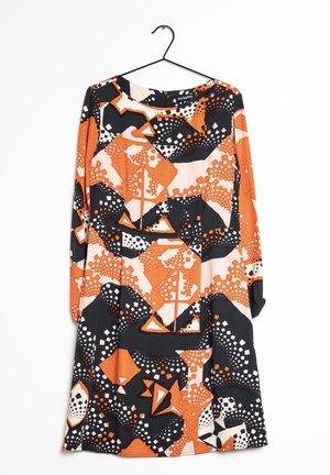 Sukienka z długim rękawem na wieszaku z abstrakcyjnym wzorem geometrycznym w kolorach pomarańczowym, czarnym i białym.