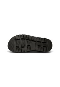 Black rubber shoe sole with textured grip patterns, featuring alternating raised and flat sections for traction and stability.