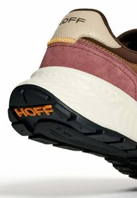 Close-up van een sneakerhak met paars suède, beige leer, bruine voering, witte zool en "HOFF" logo op de haksluiting en zwarte buitenzool.