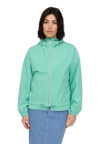 Lightweight mint green zip-up jacket with a hood, elastic cuffs, and drawstring hem. Features a logo on the chest and smooth fabric texture.