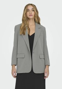 Blazer gris de rayas con solapas en pico, cierre de un solo botón y dos bolsillos delanteros. La tela parece suave con un ajuste estructurado.
