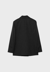 Schwarze, maßgeschneiderte Jacke mit strukturiertem Kragen, langen Ärmeln und einer dezenten gepunkteten Textur im gesamten Stoff.