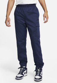 Pantalones cargo en color navy con cintura elástica, bolsillos laterales y puños en los tobillos. Hechos de una tela suave, con un logo sutil en el bolsillo.