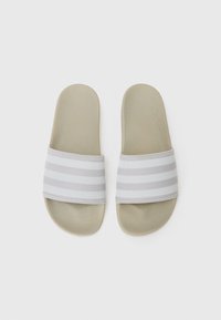 Slidesandaler med en flad, beige sål og et struktureret, stribet bånd i hvid og grå nuancer. Designet er enkelt og afslappet.