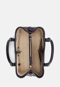 Černá kožená kabelka s béžovou látkovou podšívkou, dvěma uchy, centrálním zipovým oddílem a několika otevřenými kapsami pro organizaci.